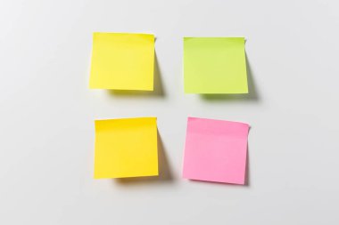 Beyaz duvarda dört tane boş renkli yapışkan not var. Şablon maketi