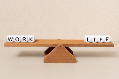 İş ve hayat kelimeleri tahtadan bir tahterevallinin üzerinde mükemmel bir şekilde dengeleniyor. Dengeyi temsil ediyor.