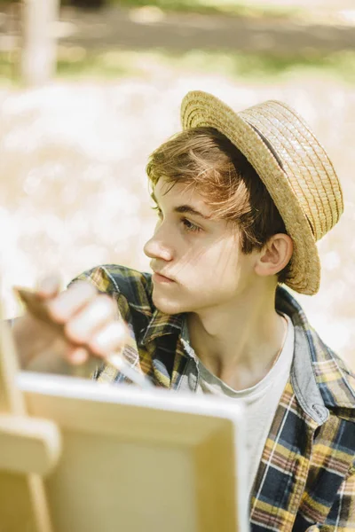 Joven Con Sombrero Paja Sienta Parque Frente Caballete Pinta Cuadro — Foto de Stock