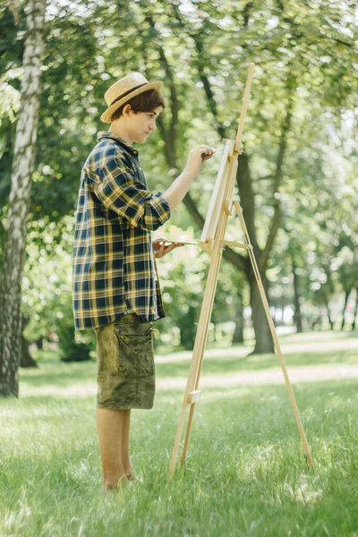 모자를 공원에 앞에서 물감으로 그림을 그리고 있습니다 예술적 작업은 자연에 — 스톡 사진