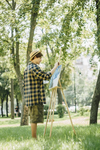 Een Jongeman Met Een Strohoed Zit Het Park Voor Een — Stockfoto