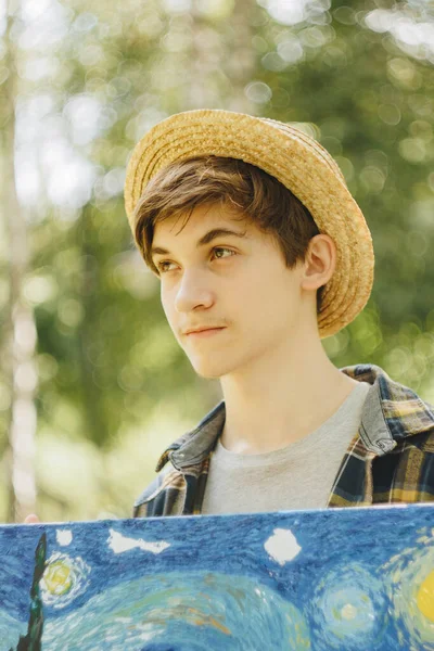Ένας Νεαρός Ψάθινο Καπέλο Κάθεται Στο Πάρκο Μπροστά Από Ένα — Φωτογραφία Αρχείου