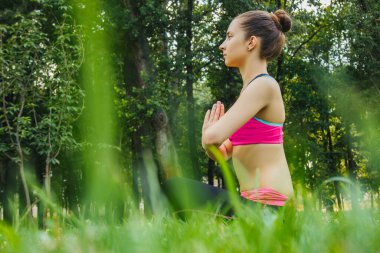 Hafif eşofmanlı Avrupalı bir kız yazın öğleden sonra parkta yoga yapıyor. Doğada jimnastik. Dışarıdaki zayıf kadın..
