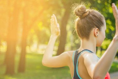 Hafif eşofmanlı Avrupalı bir kız yazın öğleden sonra parkta yoga yapıyor. Doğada jimnastik. Dışarıdaki zayıf kadın..