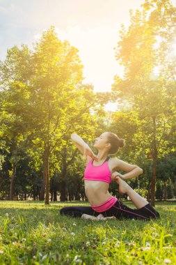 Hafif eşofmanlı Avrupalı bir kız yazın öğleden sonra parkta yoga yapıyor. Doğada jimnastik. Dışarıdaki zayıf kadın..