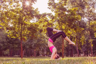Hafif eşofmanlı Avrupalı bir kız yazın öğleden sonra parkta yoga yapıyor. Doğada jimnastik. Dışarıdaki zayıf kadın..