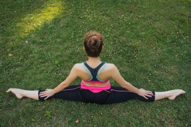 Hafif eşofmanlı Avrupalı bir kız yazın öğleden sonra parkta yoga yapıyor. Doğada jimnastik. Dışarıdaki zayıf kadın..