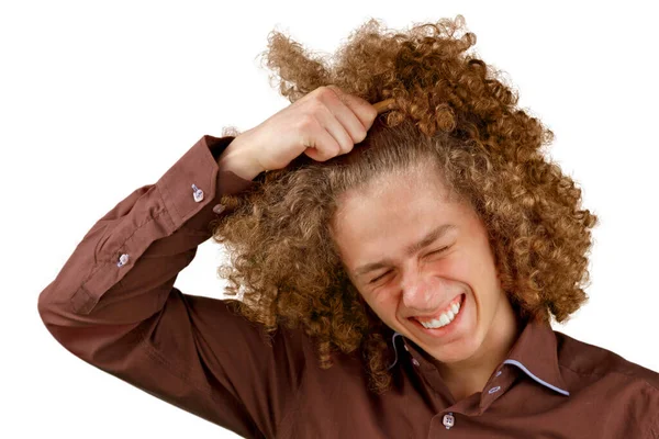 白地に茶色のシャツを着た長髪の巻き毛の男が木製の櫛を使用しています 美容室で散髪する前の感情 痛みを感じる — ストック写真