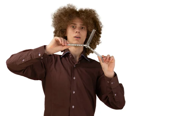 白い背景に茶色のシャツを着た長髪の巻き毛の男は 金属櫛を使用しています 美容室で散髪する前の感情 — ストック写真