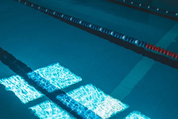 a water pool with blue transparent clear water, on which bright sunlight shines. Water lanes in the swimming pool. indoor sports field for swimming.