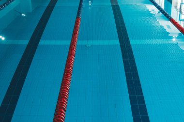 Üzerinde parlak güneş ışığının parladığı şeffaf mavi bir su havuzu. Yüzme havuzundaki su yolları. yüzmek için kapalı spor sahası.