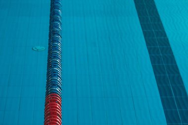 Üzerinde parlak güneş ışığının parladığı şeffaf mavi bir su havuzu. Yüzme havuzundaki su yolları. yüzmek için kapalı spor sahası.