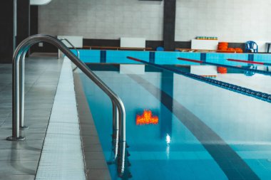Üzerinde parlak güneş ışığının parladığı şeffaf mavi bir su havuzu. Yüzme havuzundaki su yolları. yüzmek için kapalı spor sahası.