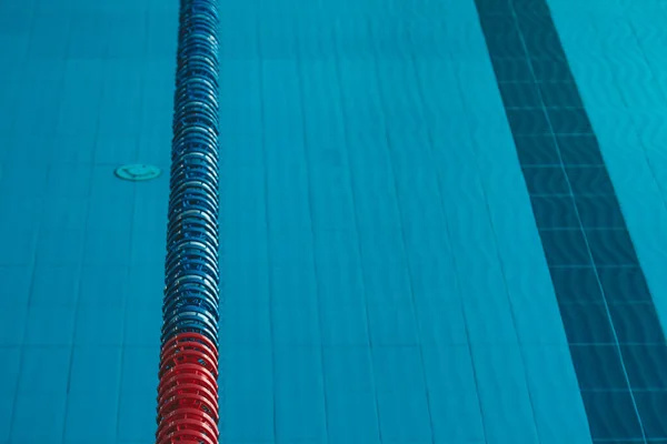 a water pool with blue transparent clear water, on which bright sunlight shines. Water lanes in the swimming pool. indoor sports field for swimming.