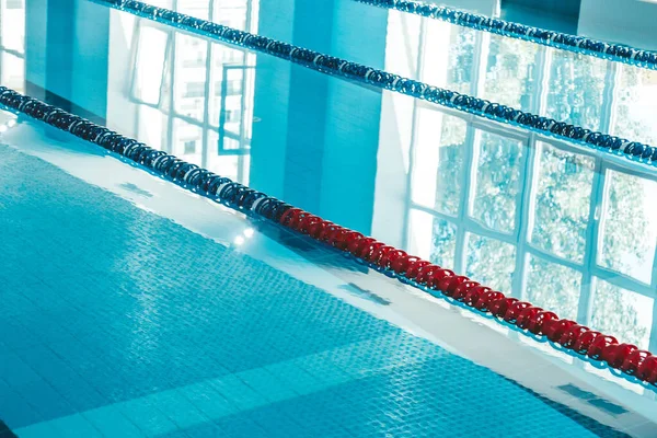 a water pool with blue transparent clear water, on which bright sunlight shines. Water lanes in the swimming pool. indoor sports field for swimming.