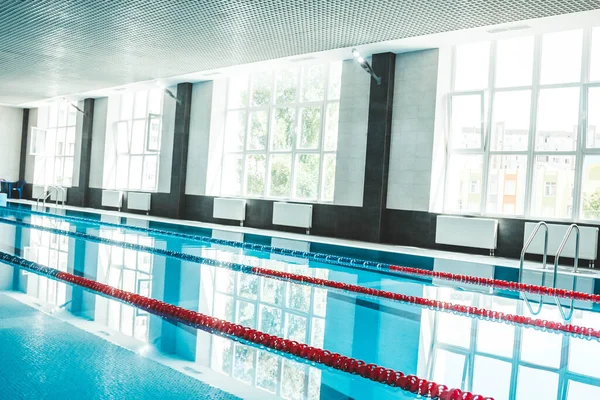 a water pool with blue transparent clear water, on which bright sunlight shines. Water lanes in the swimming pool. indoor sports field for swimming.