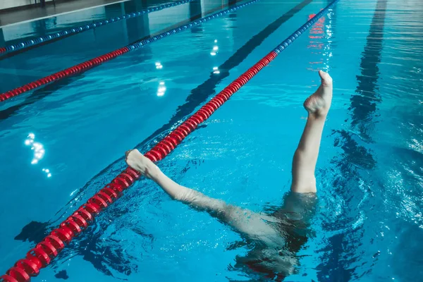 synchronized swimming athlete trains alone in the swimming pool. Training in the water upside down. Legs peek out of the water. sports figure from legs.