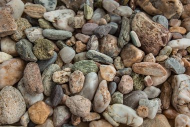 Çok renkli nehir çakıl taşları denizin yanındaki kumun üzerinde gelişigüzel duruyor. Makro fotoğrafçılık. Yakın plan kavramı, kopyalama alanı.