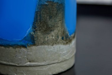 Beyaz bir duvarın arka planında beton olan ev yapımı sarı mum. El yapımı dekor yakın plan. Çatı katı biçiminde renkli mum ayrıntıları tüp şeklinde.