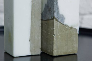 Beyaz bir duvarın arka planında beton olan ev yapımı beyaz mum. El yapımı dekor yakın plan. Çatı katı biçimindeki renkli mumların ayrıntıları küp şeklinde.