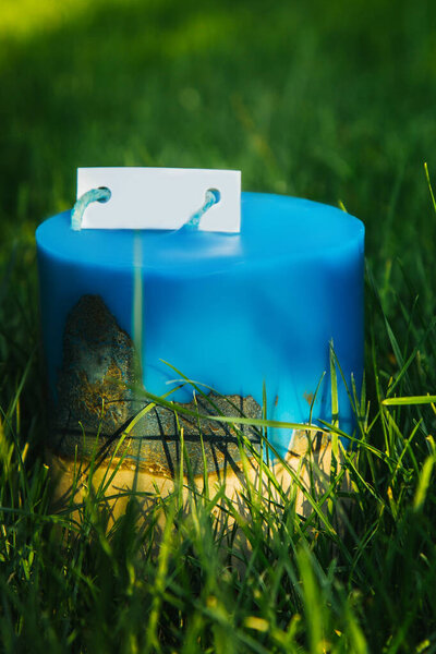 homemade multi-colored candles with concrete on a background of green grass. handmade decor close-up. Details of a colored cube and tube loft candle.