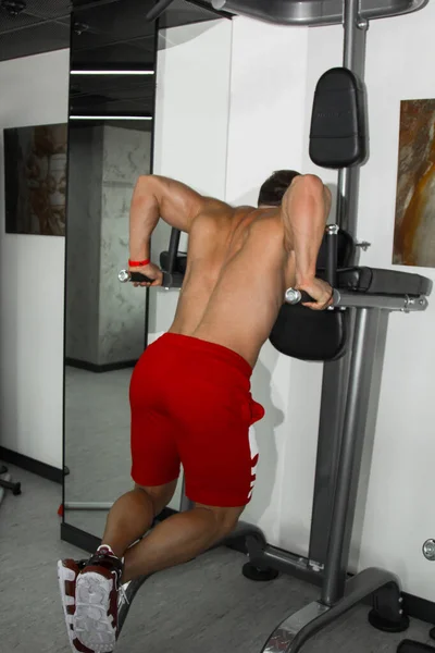一个肌肉很大的男人正在体育馆里练举重 一个精力充沛的运动员在重量级模拟器上参加体育运动 体育锻炼 — 图库照片