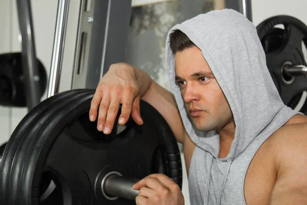筋肉の大きい男がジムで重量挙げをしています ポンプ式アスリートは 重い重量シミュレータ上のスポーツのために入る スポーツ演習 — ストック写真