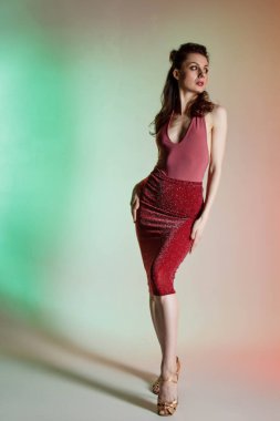 Renkli arka plan, neon ışıklar, stüdyo çekimi. Güzel elbiseli, zarif, esmer bir kadının moda portresi.