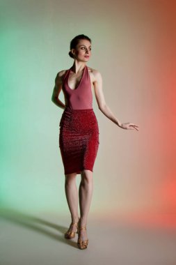 Renkli arka plan, neon ışıklar, stüdyo çekimi. Güzel elbiseli, zarif esmer bir kadının portresi. Çıplak sırt, ilginç pozlar..