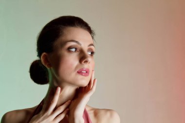 Renkli arka plan, neon ışıklar, stüdyo çekimi. Güzel elbiseli, zarif esmer bir kadının portresi. Güzellik salonu konsepti