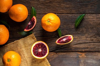 Dilimlenmiş Sicilya kanı, eski, siyah ahşap arka planda meyve portakalı bırakır. Üst görünüm.