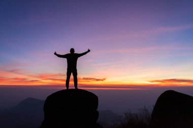 İnsan silueti dağın zirvesinde el ele tutuşur, başarı kavramı.