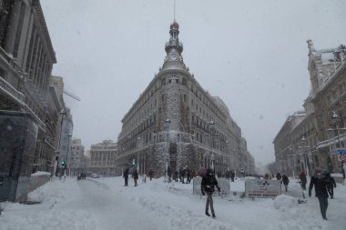 Madrid, İspanya - 09 Ocak 2021: Four Seasons Oteli 'nin önünde yürüyen insanlar, kar yağışlı bir günde, soğuk Filomena cephesinden dolayı dev bir Noel ağacı ile süslendiler..