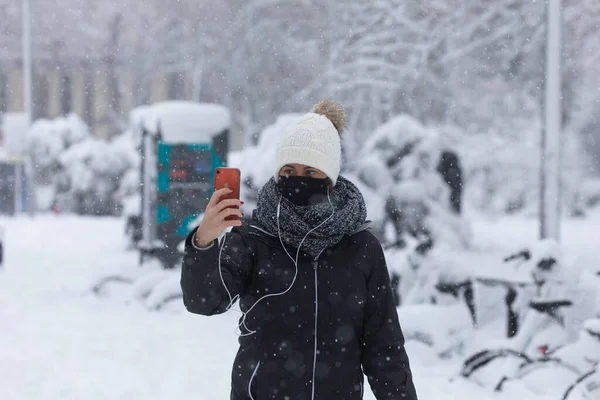 マドリード スペイン 2021年1月9日 暖かく服を着た若い女の子は フィロメナ極寒冷前線のために雪の日に メネデス ペラヨ通りに彼女の携帯電話で写真を撮ります — ストック写真