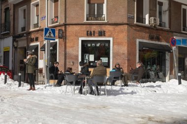 Madrid, İspanya - 10 Ocak 2021: Bir grup insan, fırtınadan sonra, karlı bir günde, Etiro bölgesinde, açık bir barda güneşlenip bira içiyorlar..