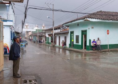 Silvia, Kolombiya - 16 Kasım 2010: Yağmurlu ve yarı boş bir sokakta, yerel bir köylü Silvia, Kolombiya, Cauca Vadisi 'ndeki kara bulutlara dikkatlice bakar..