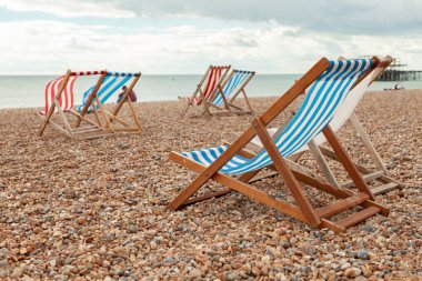 İngiltere 'nin güneyindeki Brigthon kasabasında West Pier yakınlarındaki plajda kiralanan boş kırmızı ve mavi çizgili hamaklar.