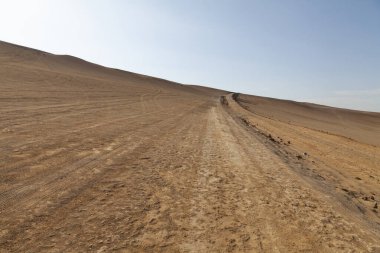 Paracas Çölü 'nde, Lagunillas Yolu' nda, Paracas Ulusal Rezervi 'ndeki Las Minas Sahili yakınlarında, Pisco, Ica, Peru' daki kum tepelerinin ve toprak pistin manzara fotoğrafı..