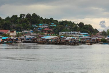 Sorong, Endonezya - 18 Ekim 2019: Waisai 'nin Sorong feribotuna vardığı yere yakın, Batı Papua' nın Sorong kasabasındaki deniz kenarındaki mütevazı küçük evlerin silüeti.