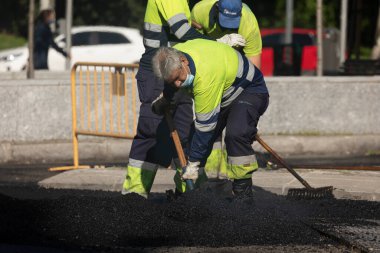 Madrid, İspanya - 5 Mayıs 2021: Madrid, Retiro 'da sokakları bakım ve asfaltlama yapan işçiler, asfalt kaldırım makinesi ve rulo işçilerinin çalışmalarını tamamlıyorlar.