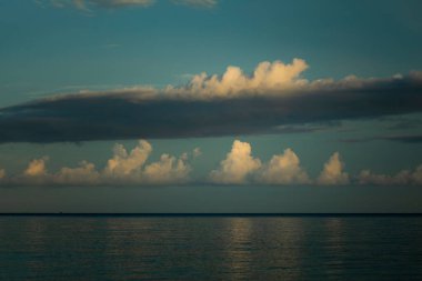 Pasifik Okyanusu 'nun ufuklarında, gün batımında Batı Papua, Endonezya' daki Raja Ampat adalarından geçen devasa sakin bulutlar.