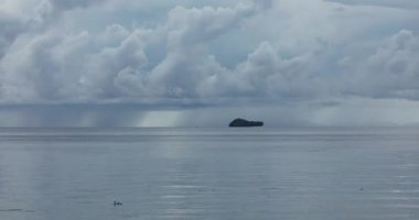 Yağmurlu bir günde, ufukta ve küçük Friwin adalarından birinde Raja Ampat, Batı Papua, Endonezya 'dan geçen devasa fırtına bulutlarının videosu.