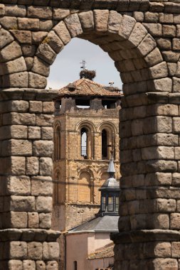 Kilisenin çan kulesi ve leylek yuvaları Santos Justo y Pastor, Segovia 'nın su kemerinden geçiyor.