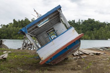 Kıyıda karaya vurmuş eski, ahşap bir tekne, suya yakın yatar ve terk edilir, Raja Ampat, Endonezya