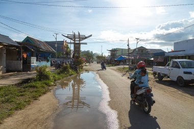 Waisai, Endonezya - 17 Ekim 2019, Waisai şehir merkezini geçerken küçük bir kız annesinin arkasını kollayarak motosikletle seyahat ediyor.