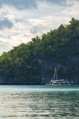 Friwin, Endonezya - 14 Ekim 2019: Bir turist botu, katamaran tipi yelkenli, büyük bir ada olan Raja Ampat, Batı Papua 'nın yanında yavaşça yelken açar.