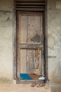 Friwin, Raja Ampat, Batı Papua, Endonezya 'daki mütevazı küçük bir evde yıpranmış ahşap bir kapının önünde parmak arası terlikler.