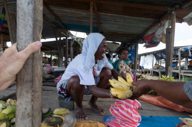 Meyve tezgahında satıcı olarak çalışan Papue 'lu bir kadın bana muz satarken aynı zamanda animasyonla, Sorong, West Papua, Endonezya' da gülüyordu.