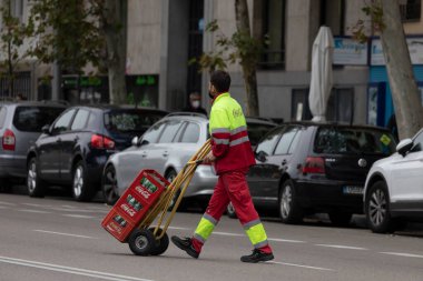 Madrid, İspanya - 28 Ekim 2020: The Coca-Cola Company 'den bir işçi, teslimatçı, Avenida Menedez Pelayo' da birkaç kutu boş cam şişeyle yürüyor.