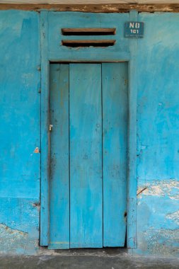 Eski ahşap bir kapı, maviye boyanmış, Togian Adaları, Sulawesi, Endonezya 'nın Kulingkinari bölgesinde küçük bir köyün mütevazı evlerinden birinde..